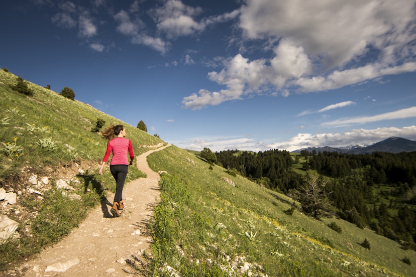 A woman walking a trail on a hillside near Bozeman, Montana