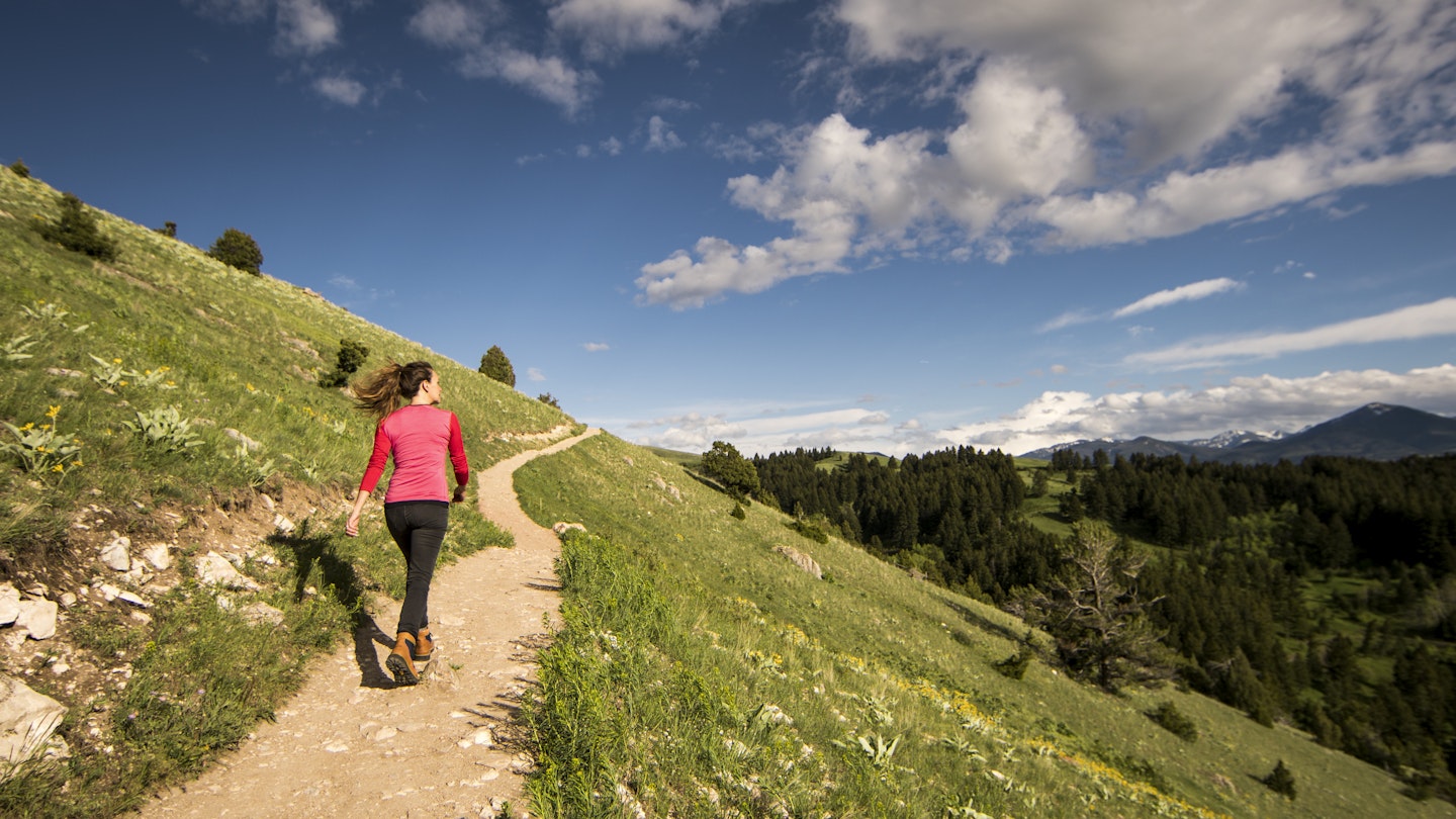 A woman walking a trail on a hillside near Bozeman, Montana