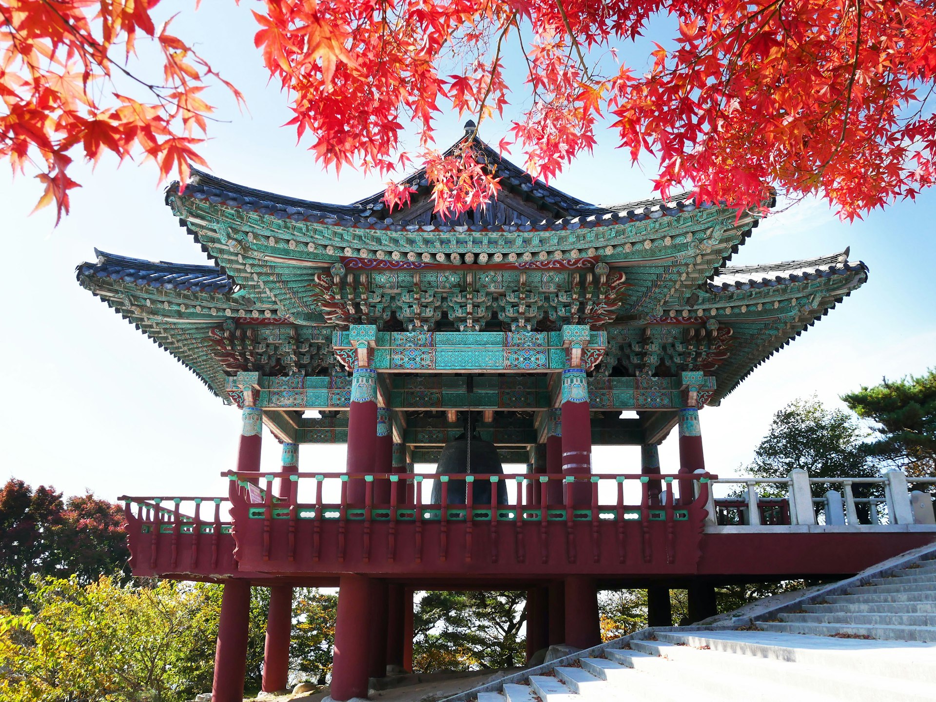 Red maple leaves in the foreground, in front of the bell pavilion at Seokguram Grotto in Gyeongju, South Korea.