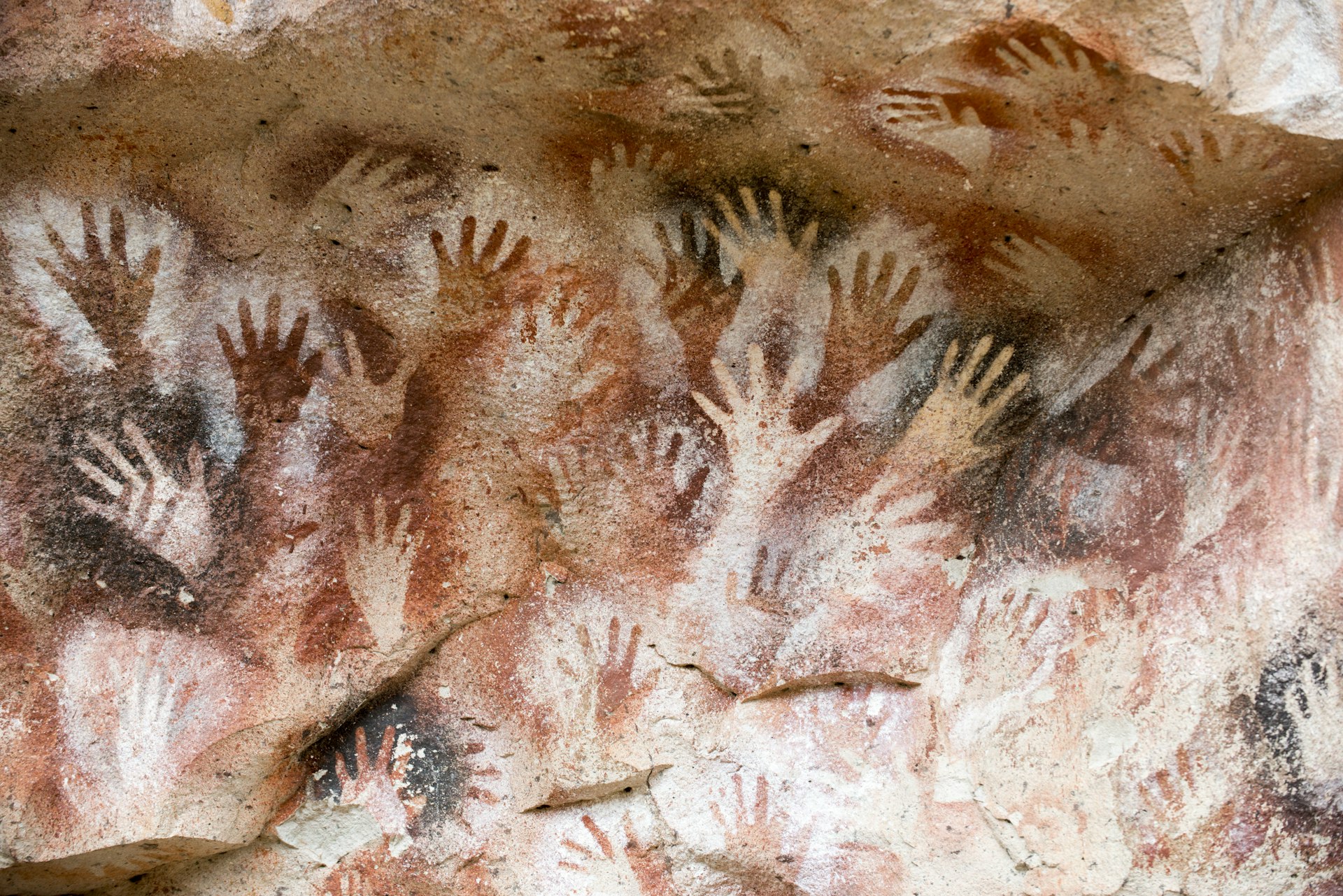Scores of hands painted in reds, yellows and blacks in a cave that make up Argentina's oldest rock art at Cueva de las Manos, dating from 6370 BC.