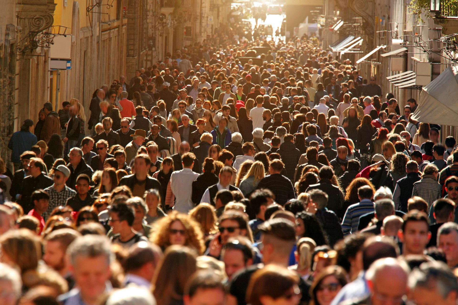 A large group of people crowding Rome's downtown streets in a sunny day.