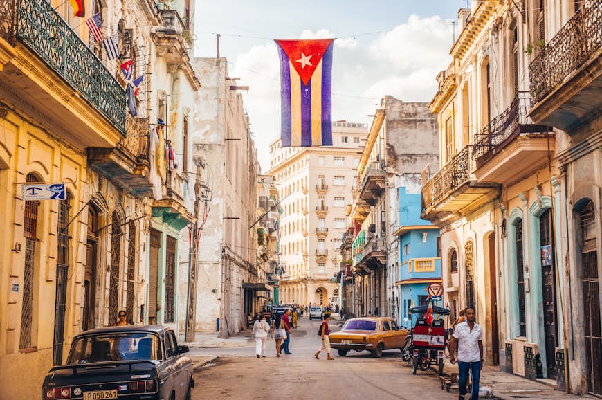 A Cuban flag with holes waves over a street in Central Havana