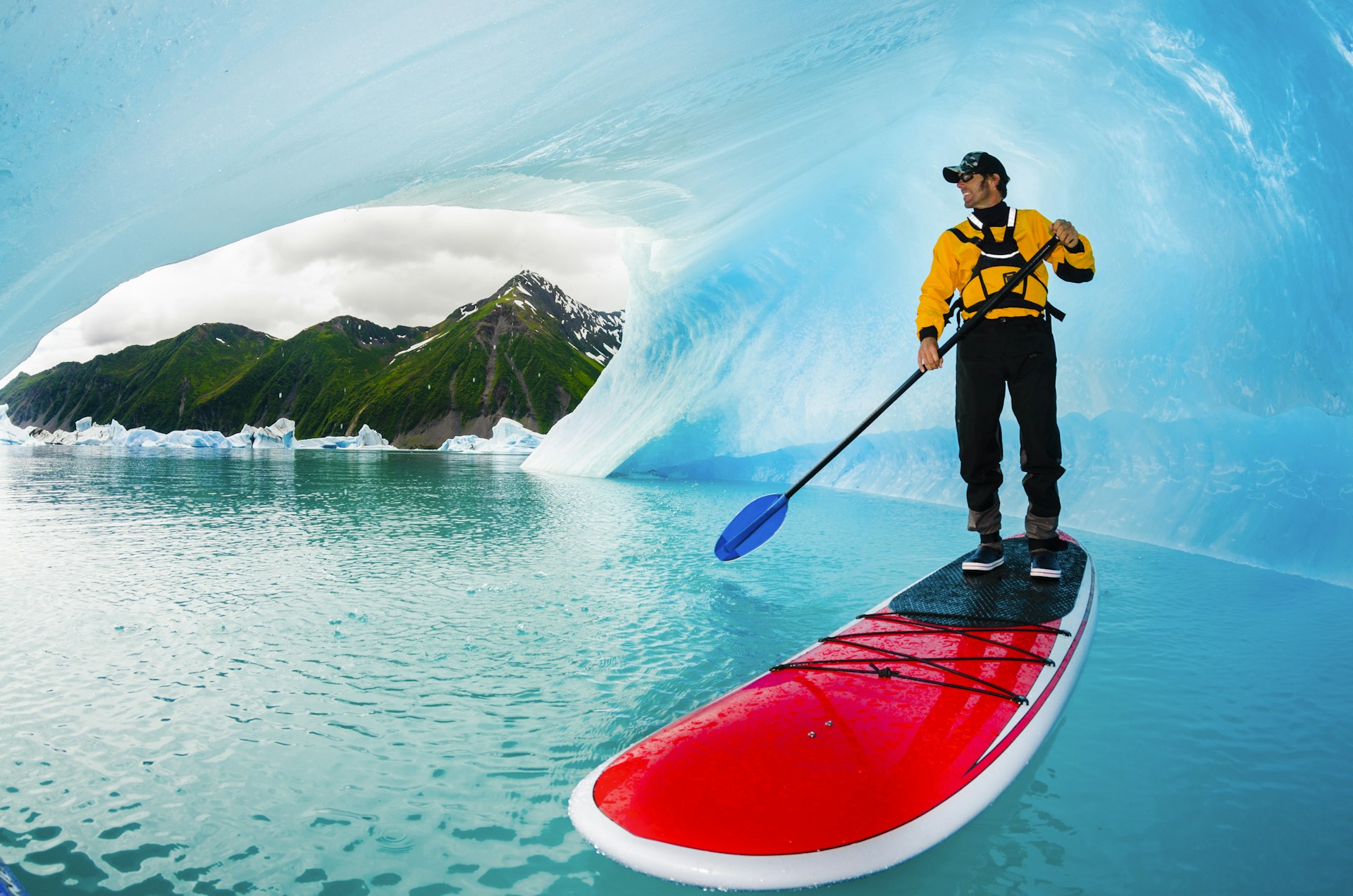 A man stand-up paddleboarding in an iceberg cavern on Bear Lake