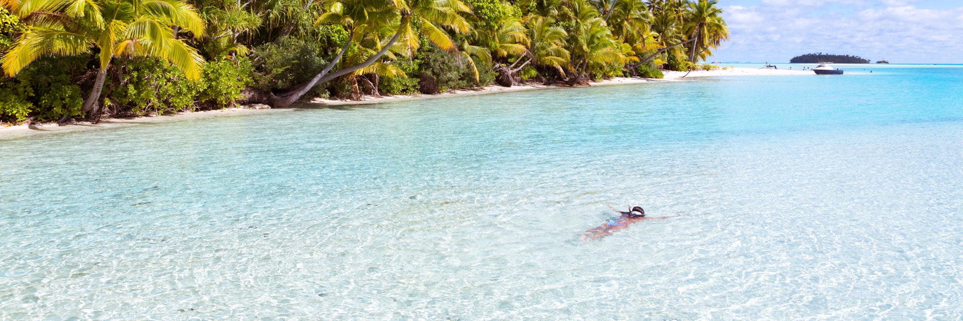 Woman in bikini snorkeling in the crystal clear water of the famous beach of Tapuaetai (One Foot Island), a small islet in the south-east of the lagoon of Aitutaki, Cook islands.