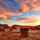 Bright orange clouds above rock formations in Goblin Valley State Park during sunset.