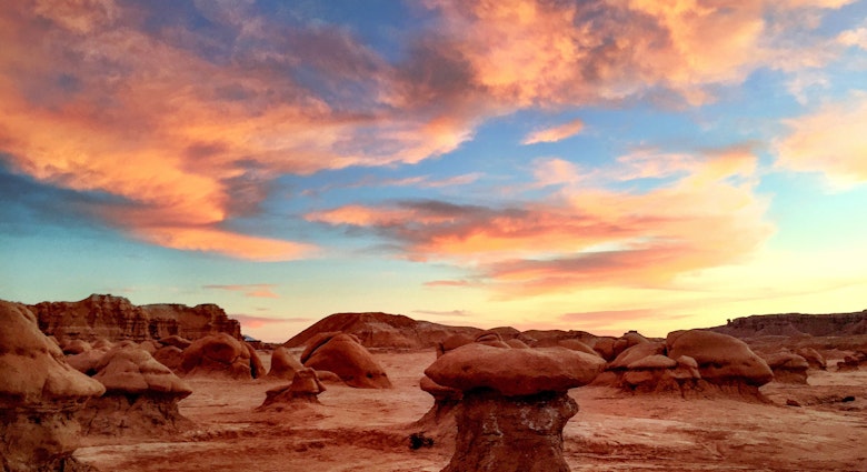 Bright orange clouds above rock formations in Goblin Valley State Park during sunset.