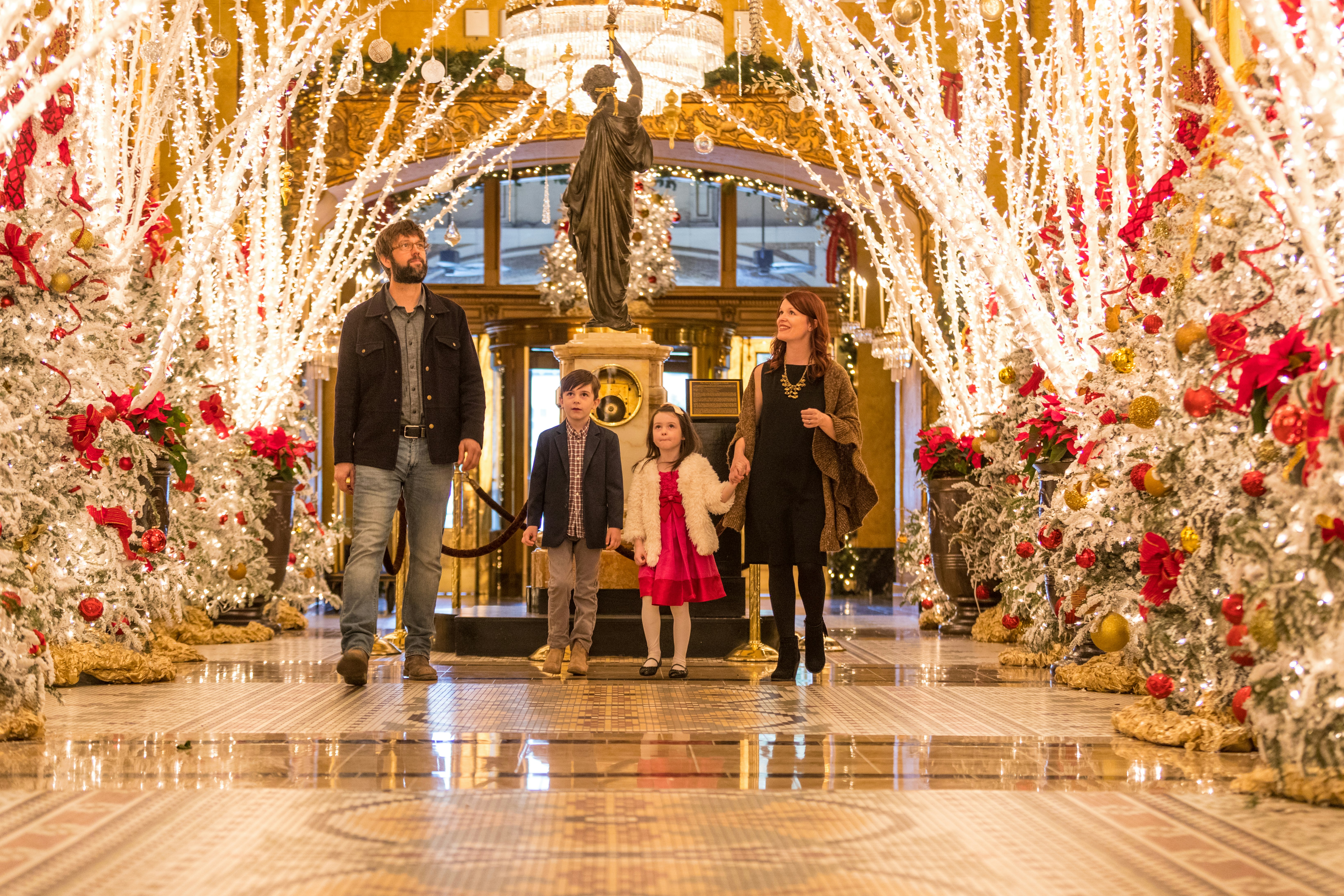 A family walks through the lobby of The Roosevelt to look at Waldorf Wonderland, a block-long display of Christmas trees, white tree lights and other holiday decorations