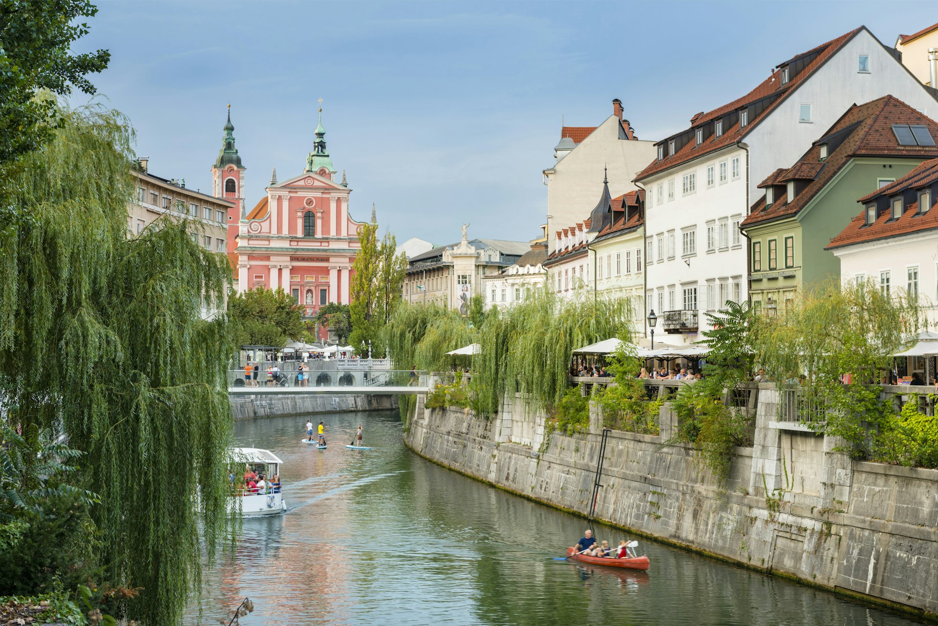 Boats and paddle boarders travel down the tree-lined Ljubljanica River, which flows through the centre of Ljubljana. 