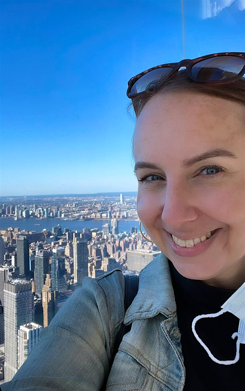 A woman takes a selfie in front of the New York city scape. 