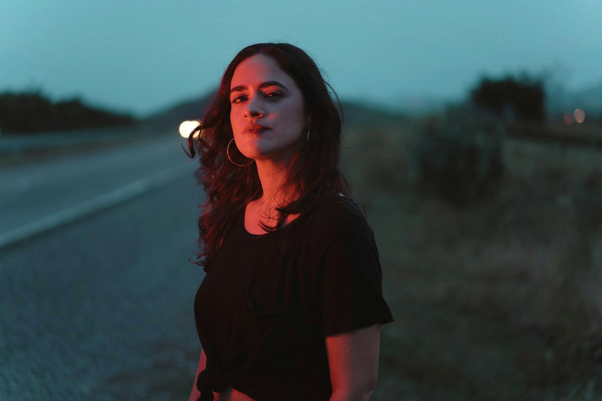 Puerto Rican singer Neysa looks into the camera. She's wearing a dark t-shirt. 