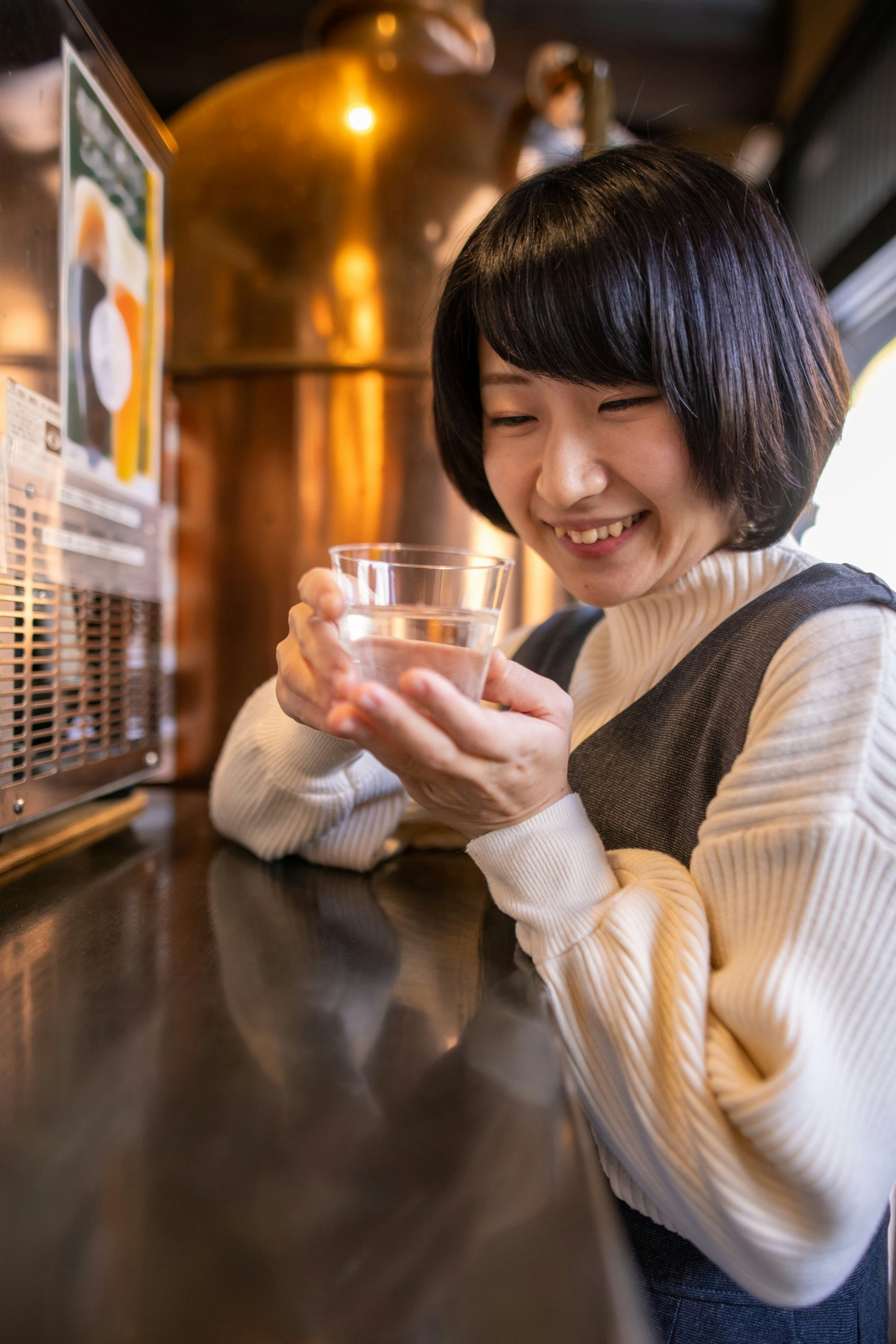 Happy young woman holding glass of 'saki' (Japanese rice wine) at traditional Japanese 'Onsen' district