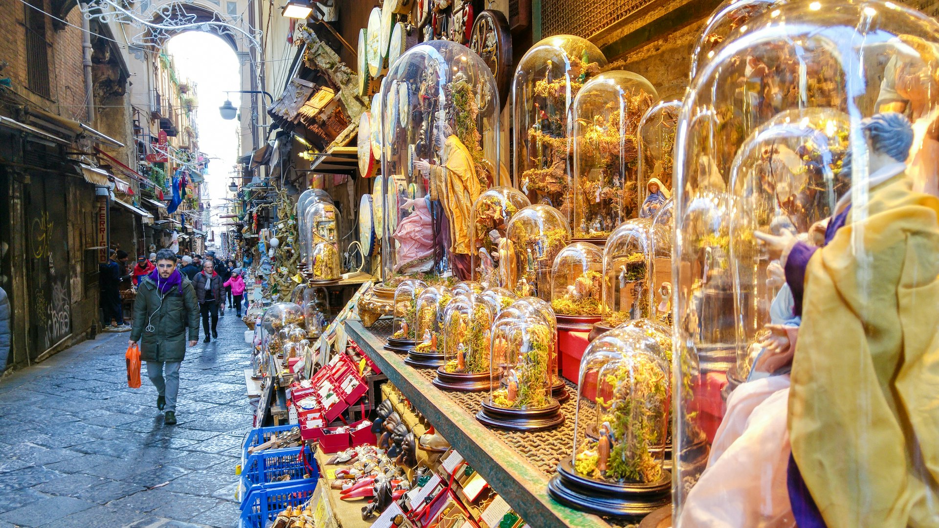 A view down San Gregorio Armeno street in Naples with a shop displaying nativity figures on the right