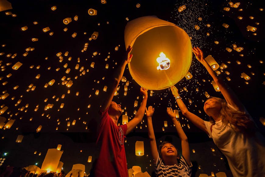 Thai family releasing paper lanterns to worship buddha's relics in Yi Peng Festival Chiang Mai