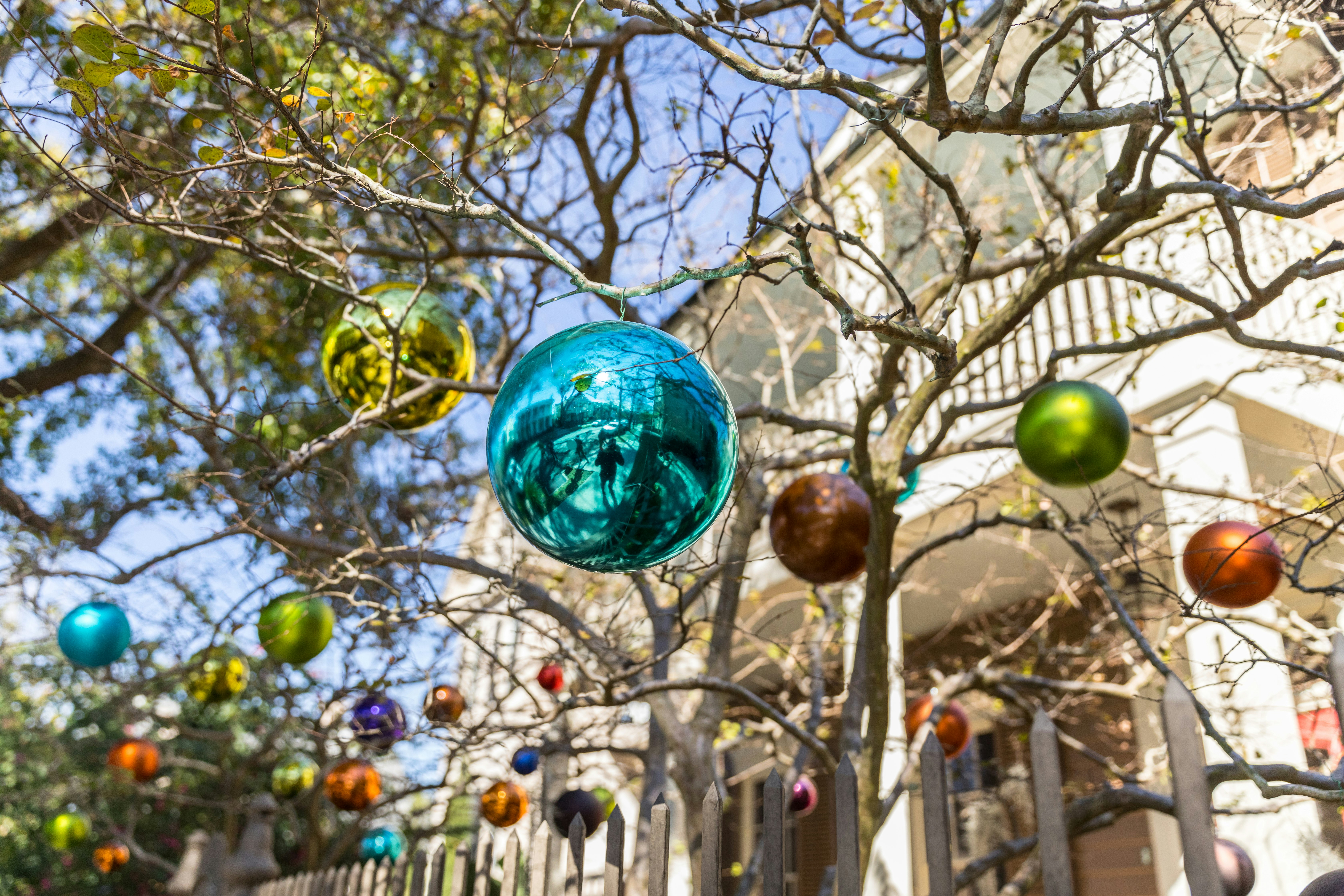 Christmas ornaments hang from a tree outside the front of a grand house in New Orleans