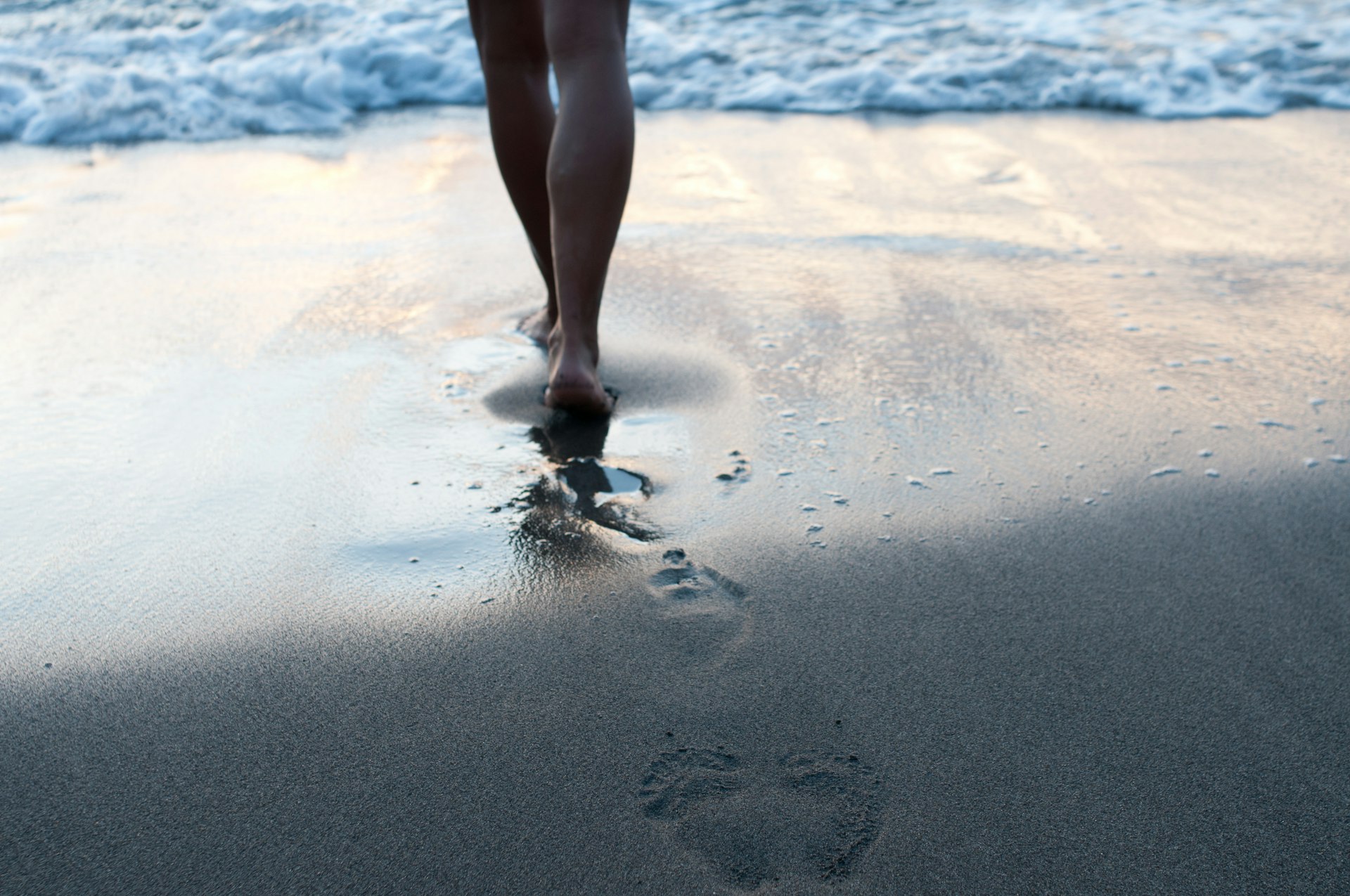 Closeup of legs of a woman walking into tide on the beach in St Lucia 