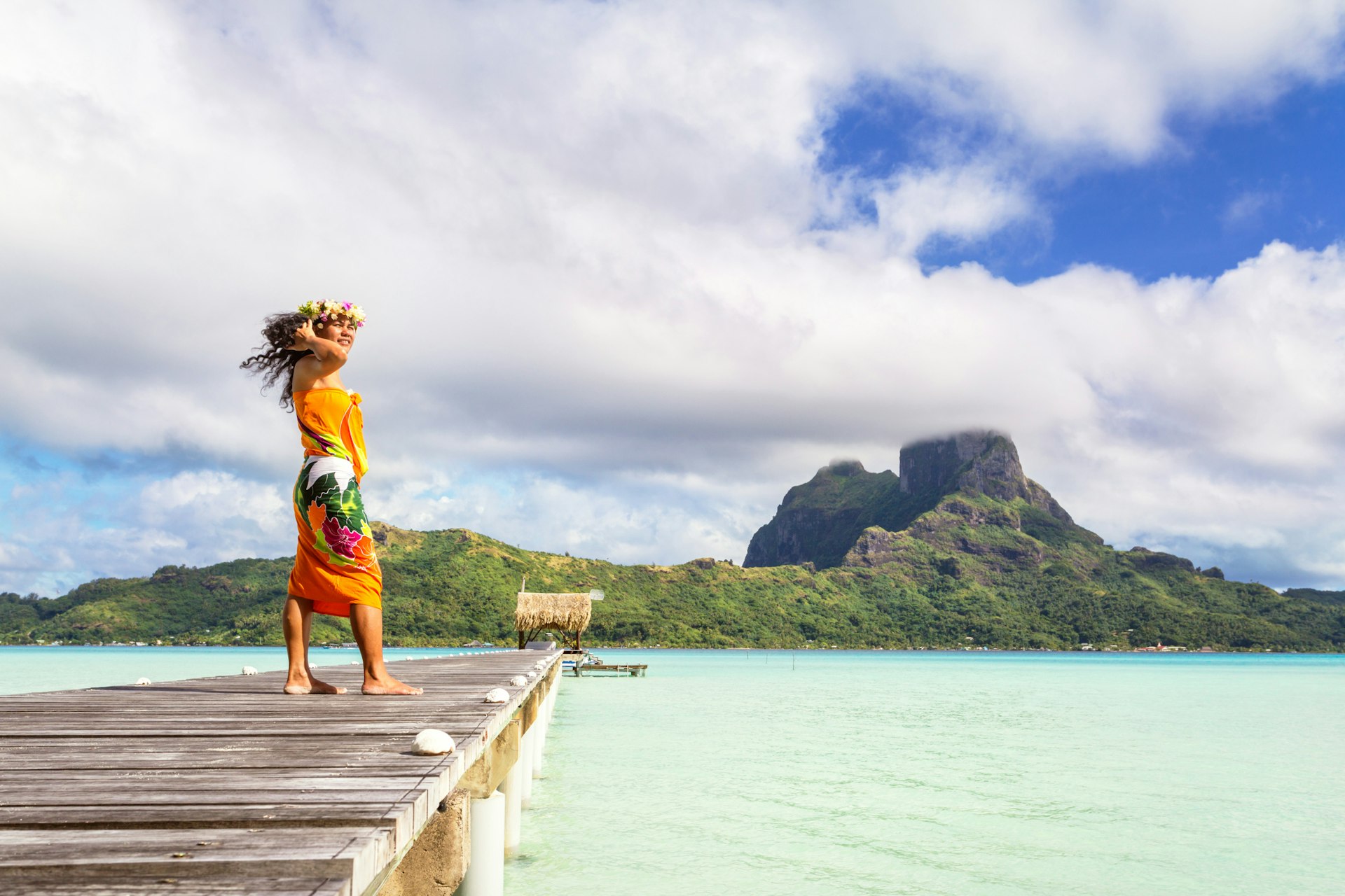A local woman standing on a jetty wearing a colorful sarong, Bora Bora lagoon
