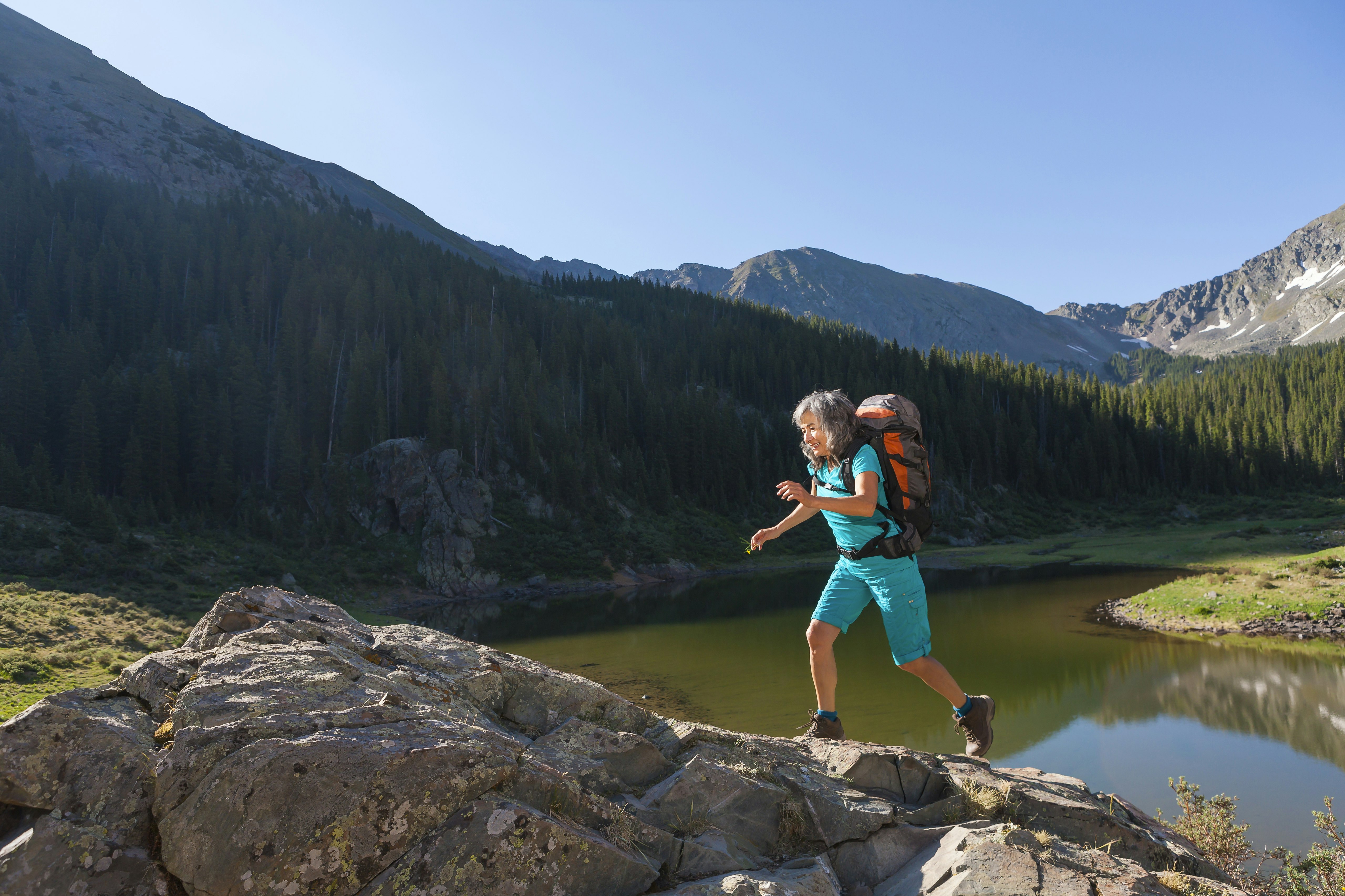 A woman hiking on a boulder near a lake