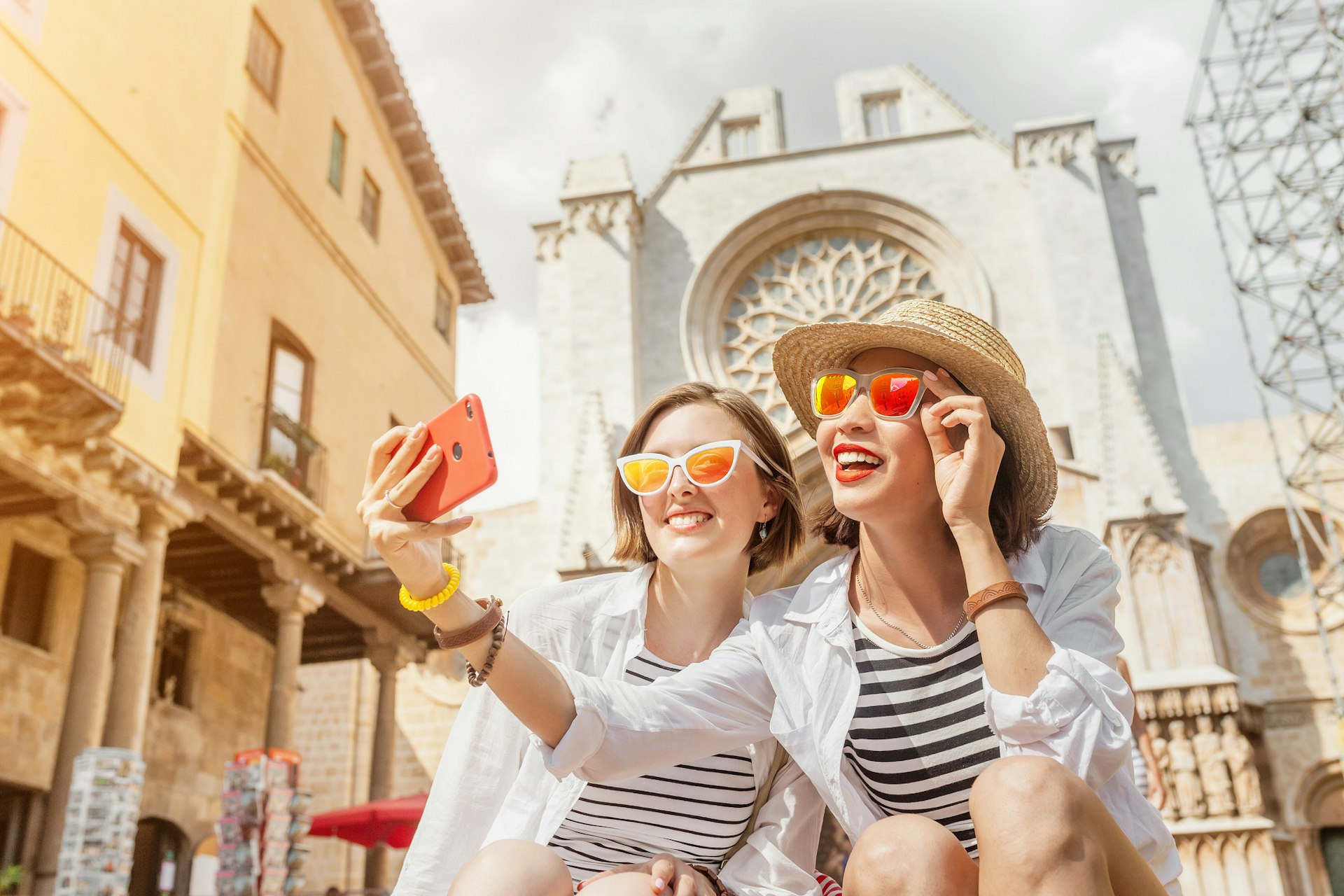 Two women smile for a selfie near the Cathedral in Tarragona city