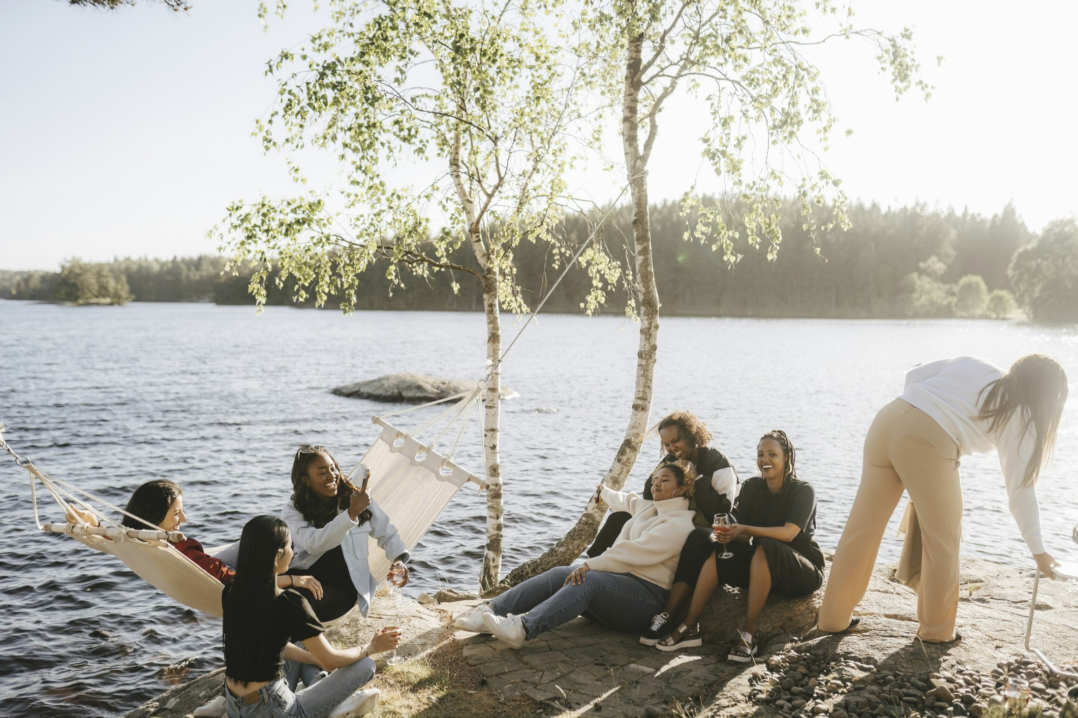 A group of female friends hanging out by a lake on sunny day