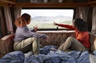 Young female friends pointing while looking through window in motor home