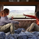 Young female friends pointing while looking through window in motor home