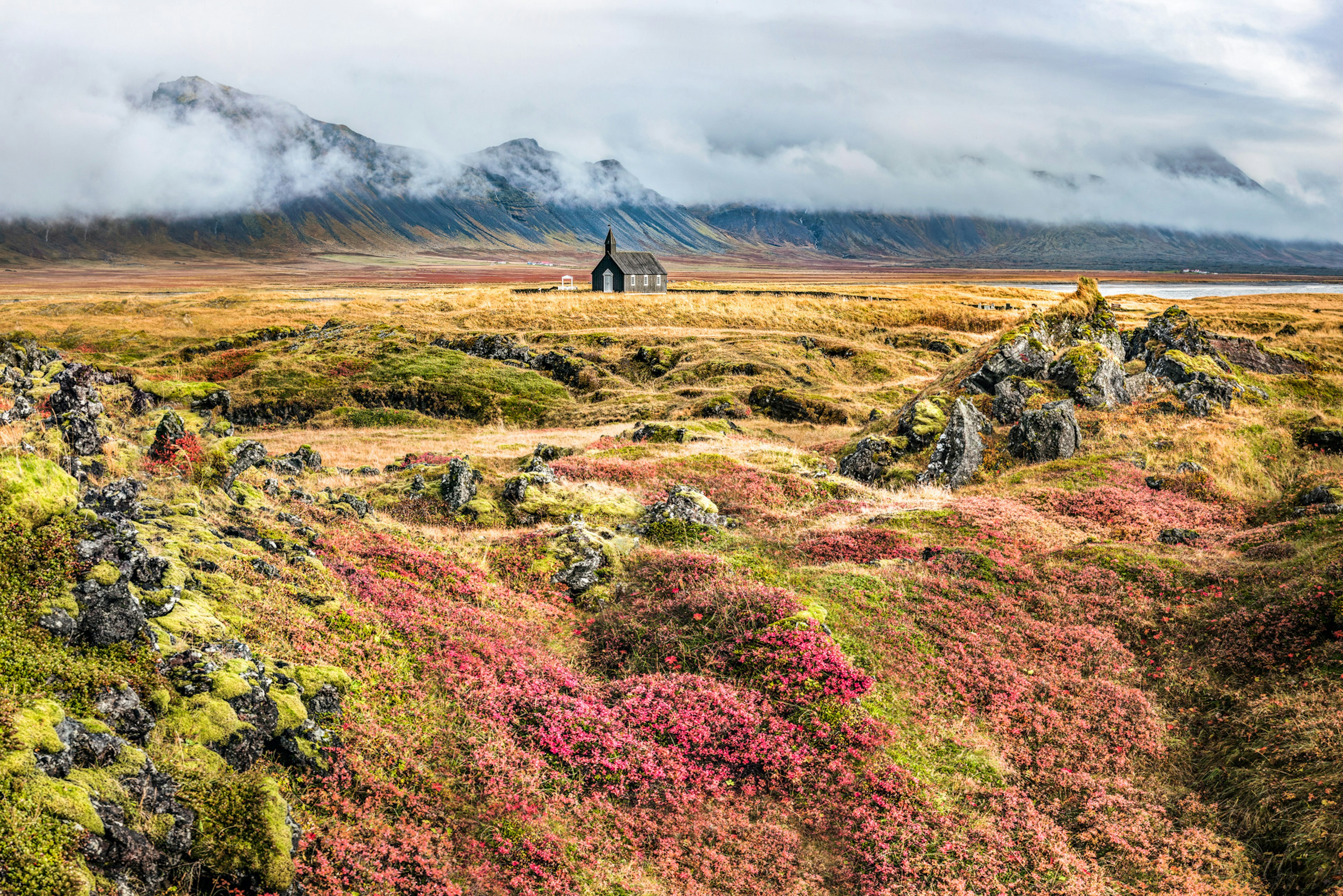 A solitary church in the middle of a volcanic field covered with colorful plants