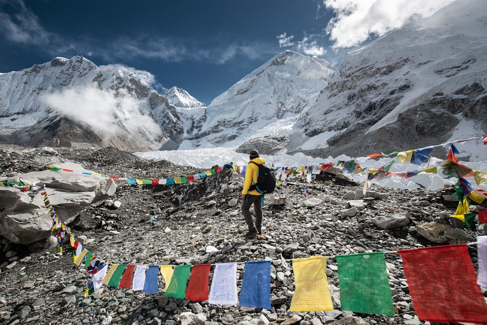 A trekker walking passed by Tibetan Prayer Flags at Everest Base Camp, Nepal.