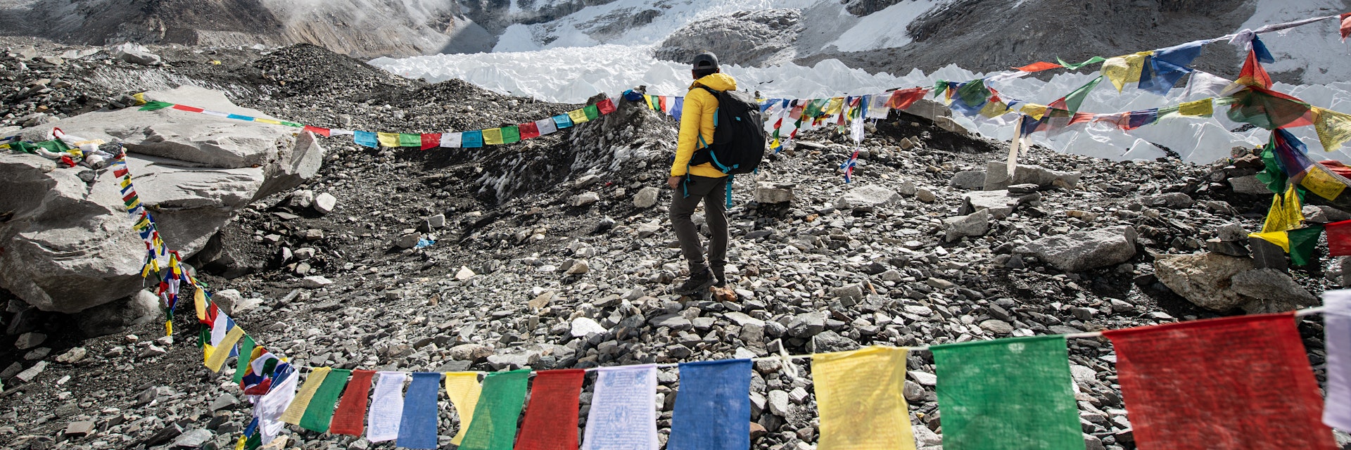 A trekker walking passed by Tibetan Prayer Flags at Everest Base Camp, Nepal.