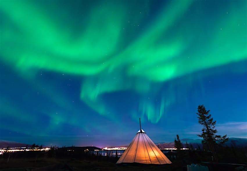 Traditional Sami reindeer-skin tents (lappish yurts) in Troms region of Norway with the northern lights in the skyional,Sami,Reindeer-skin,Tents,(lappish,Yurts),In,Troms,Region,Of