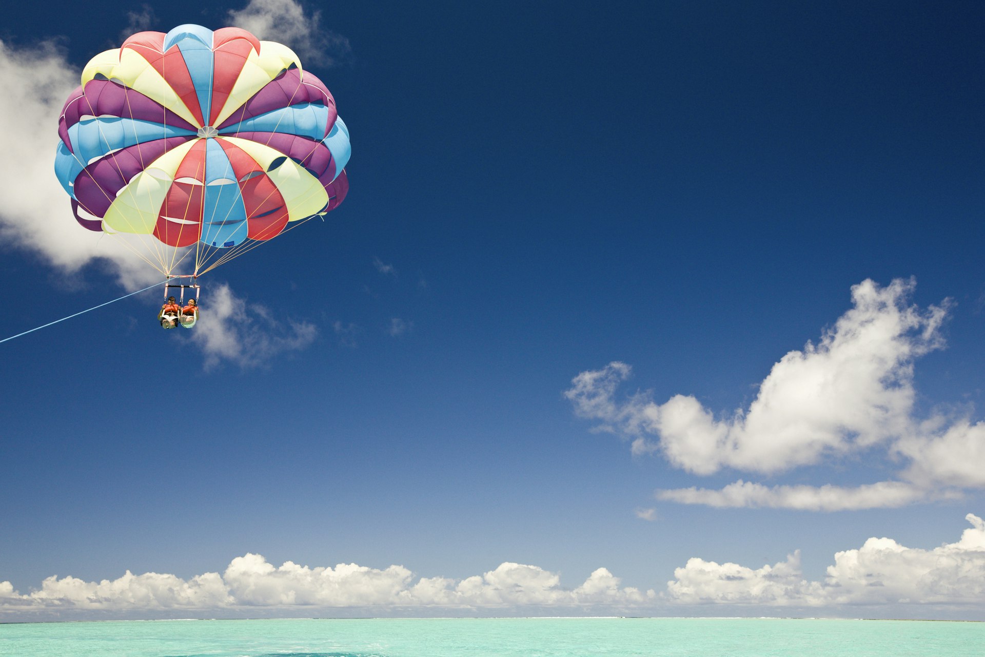 A couple parasailing beneath a colorful parachute in Bora Bora