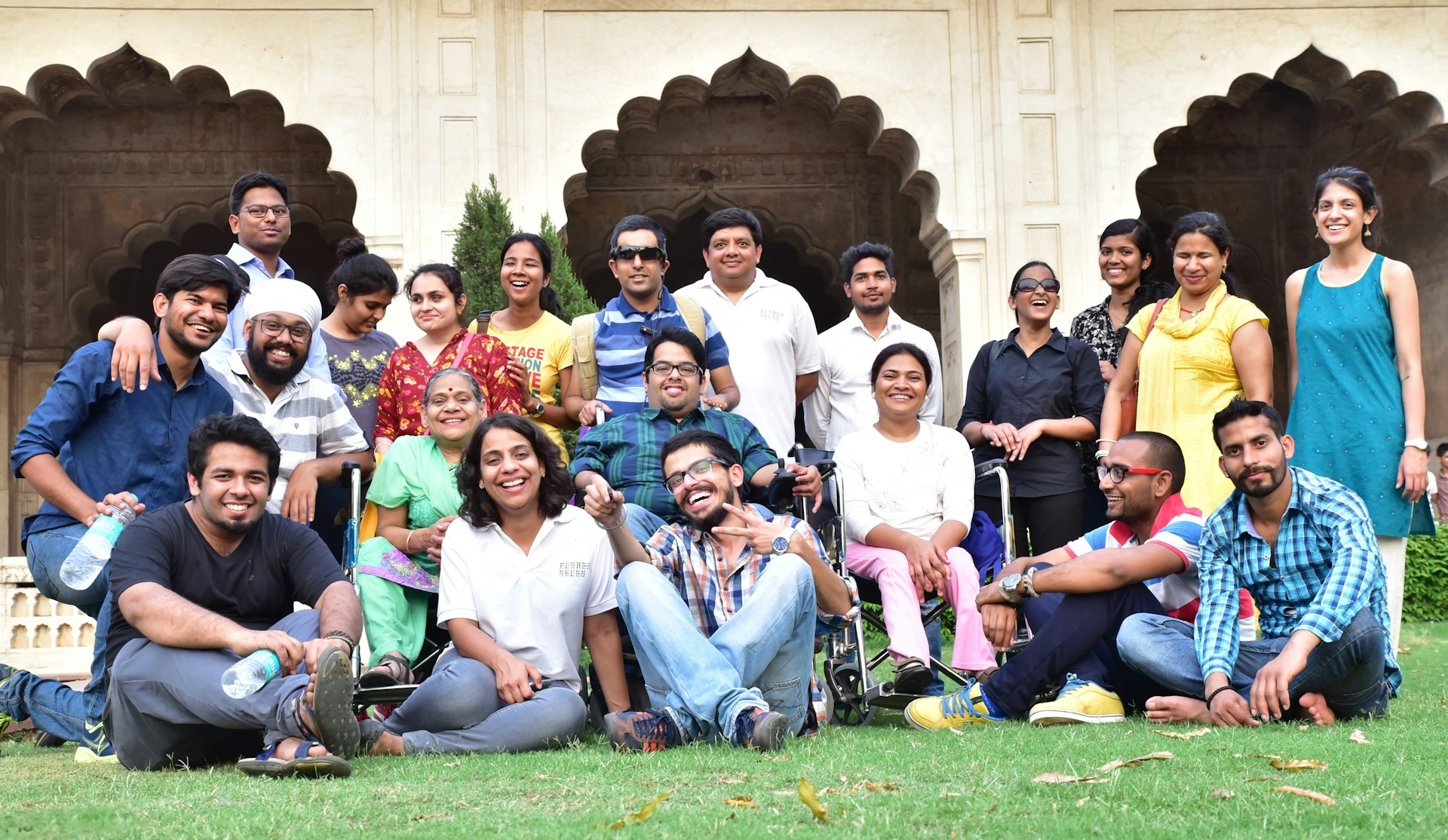 A group shot of a tour group posing in front of a South Asian monument.