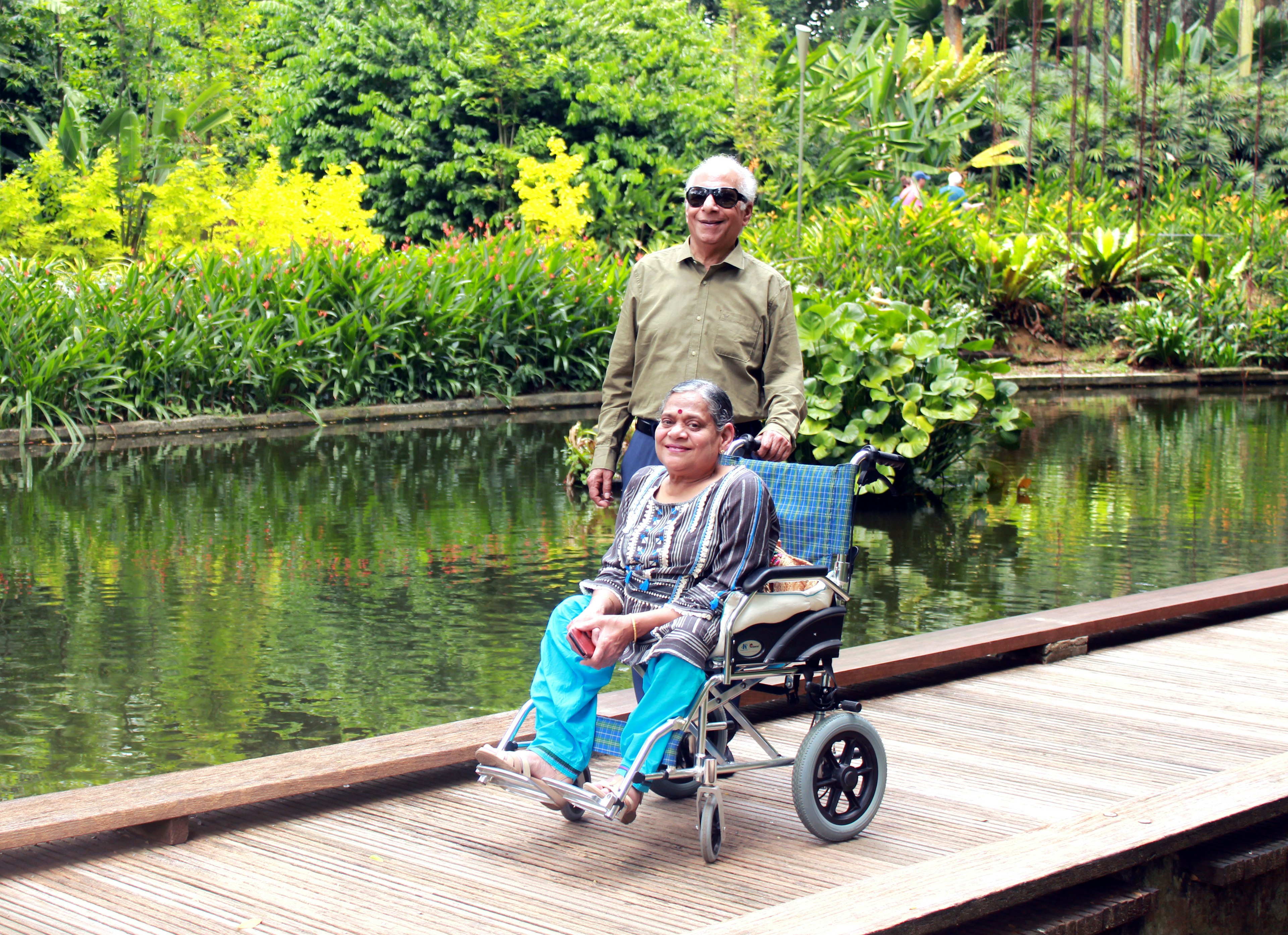 Arora's parents posing on a bridge with a tropical backdrop.