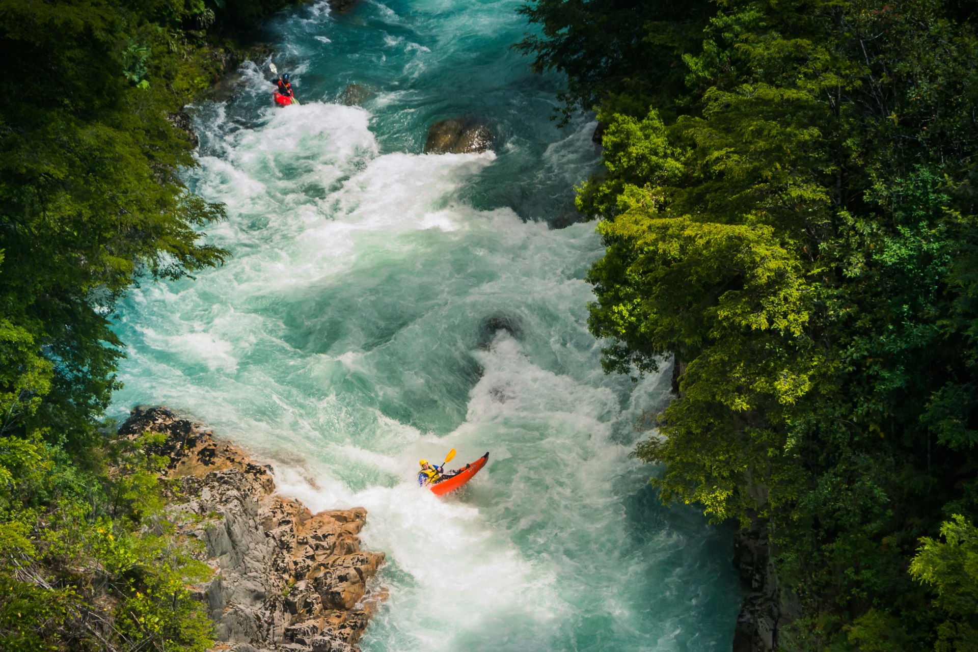 A rafter goes down white water rapids in a wide and furious river