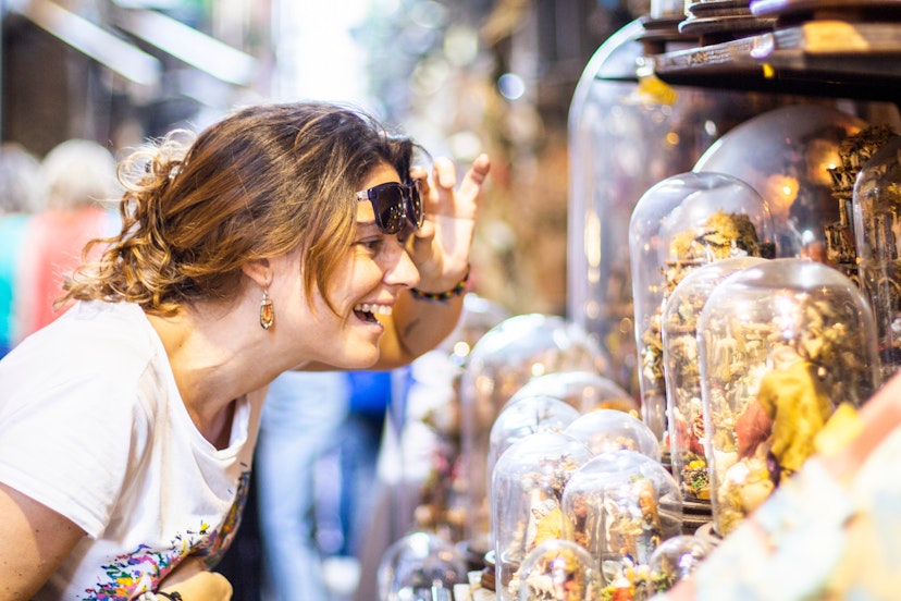 Smiling woman looking at glass-domed items at a street market in Naples..