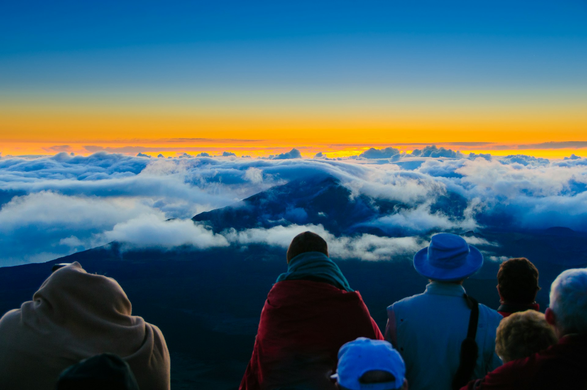 Sunrise over clouds and distant mountains from on top of Haleakala Crater, Maui, Hawaii, USA