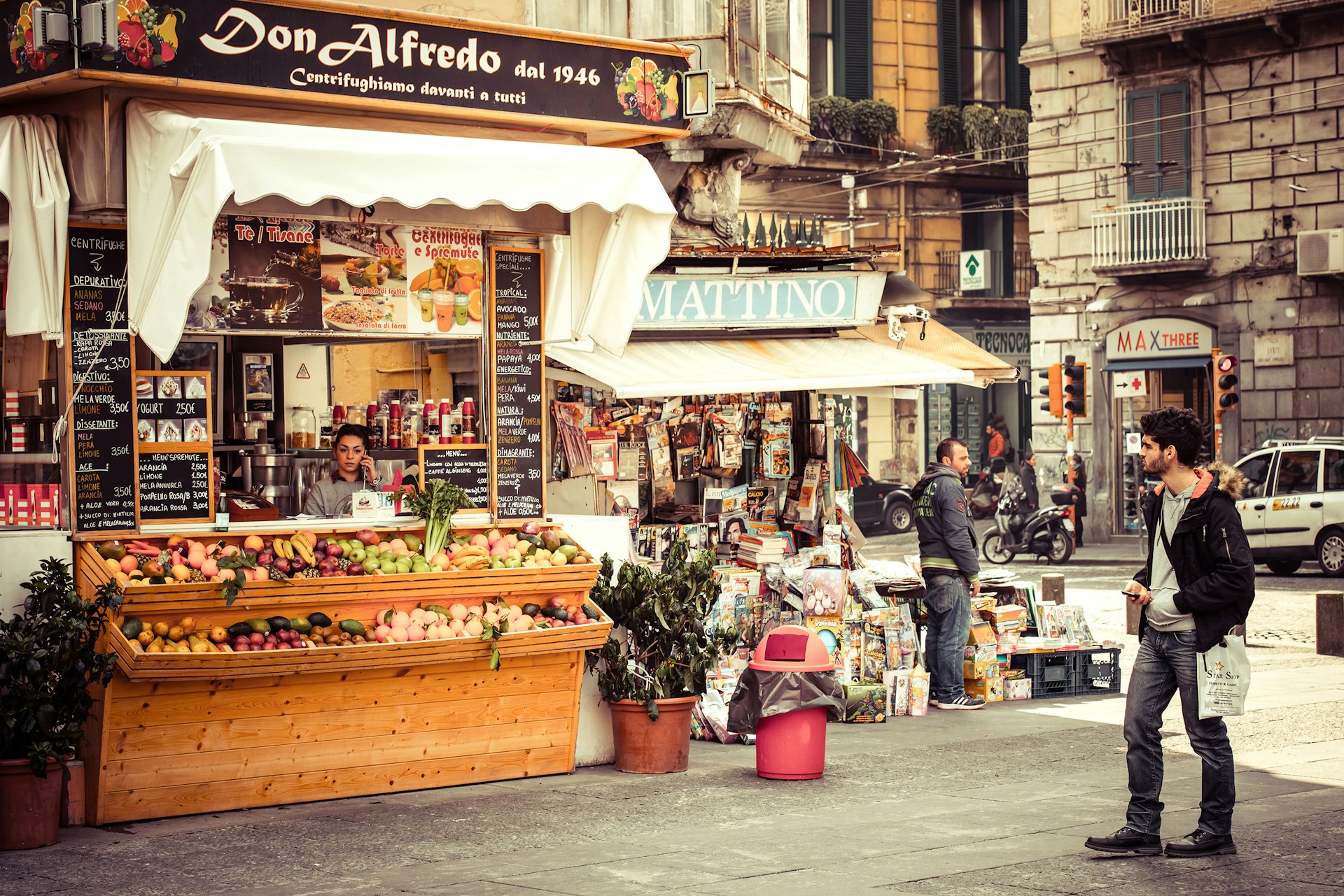 A man stands looking at a small fast food cafe and shop in the historical center of Naples, Italy