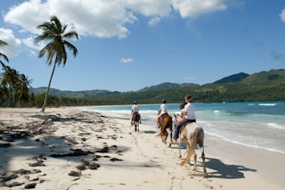 Las Galeras, Dominican Republic - 25 january 2002: people riding horses on the beach of Rincon near Las Galeras on Dominican Republic