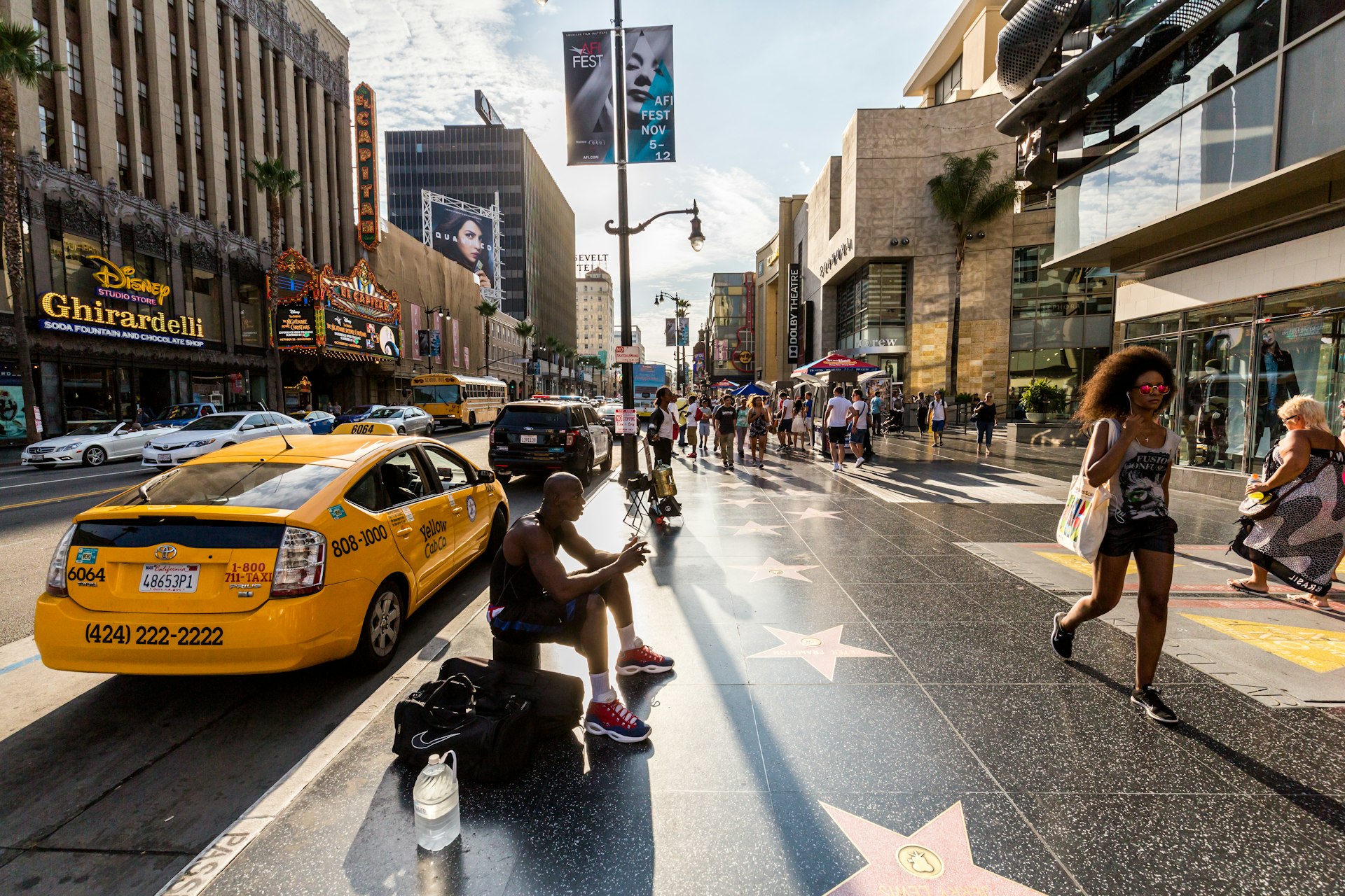 Views of the Walk of Fame and the Buildings at the Hollywood Boulevard with a woman walking in the foreground