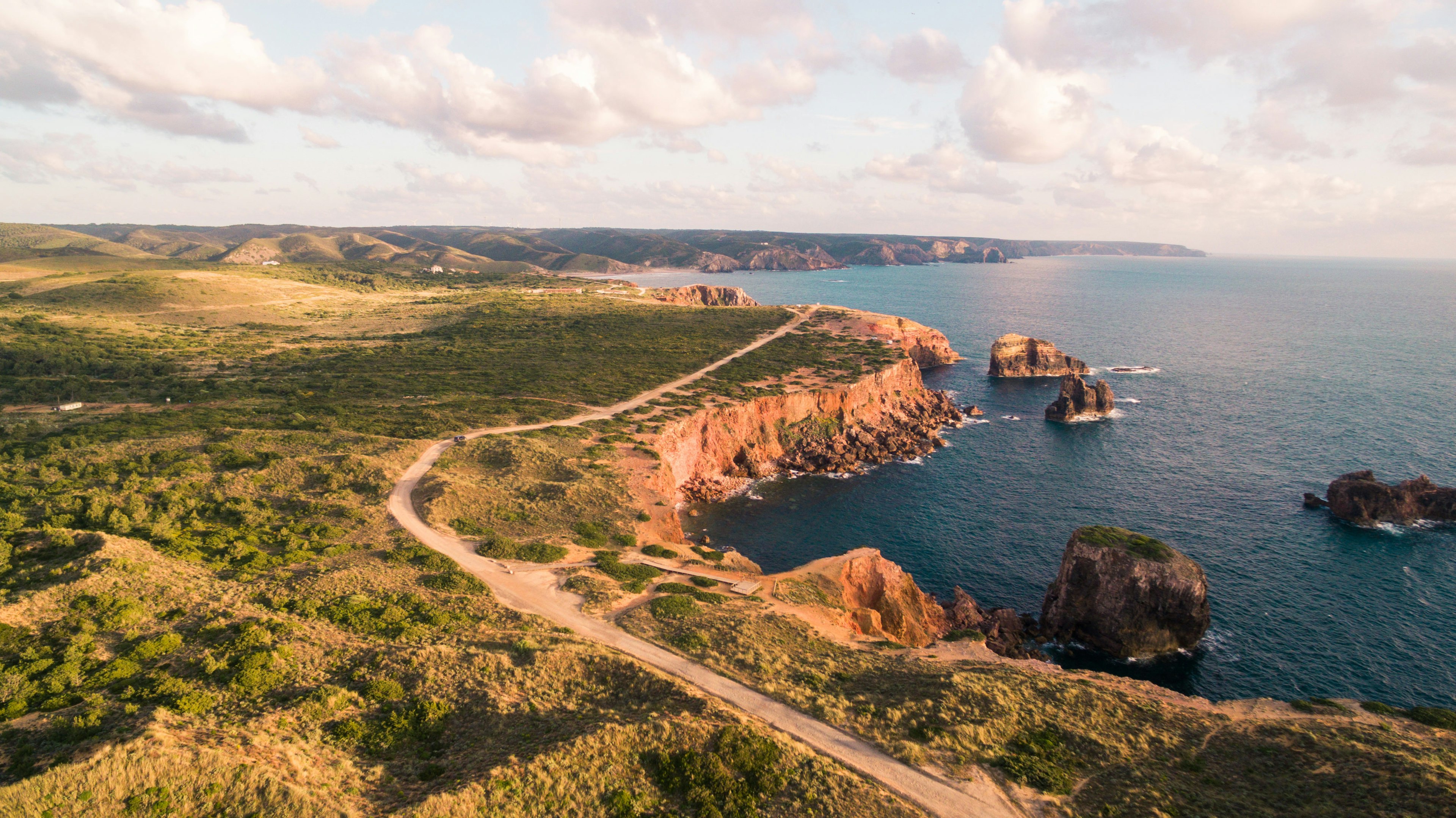 An aerial shot of a hiking path running along coastal cliffs