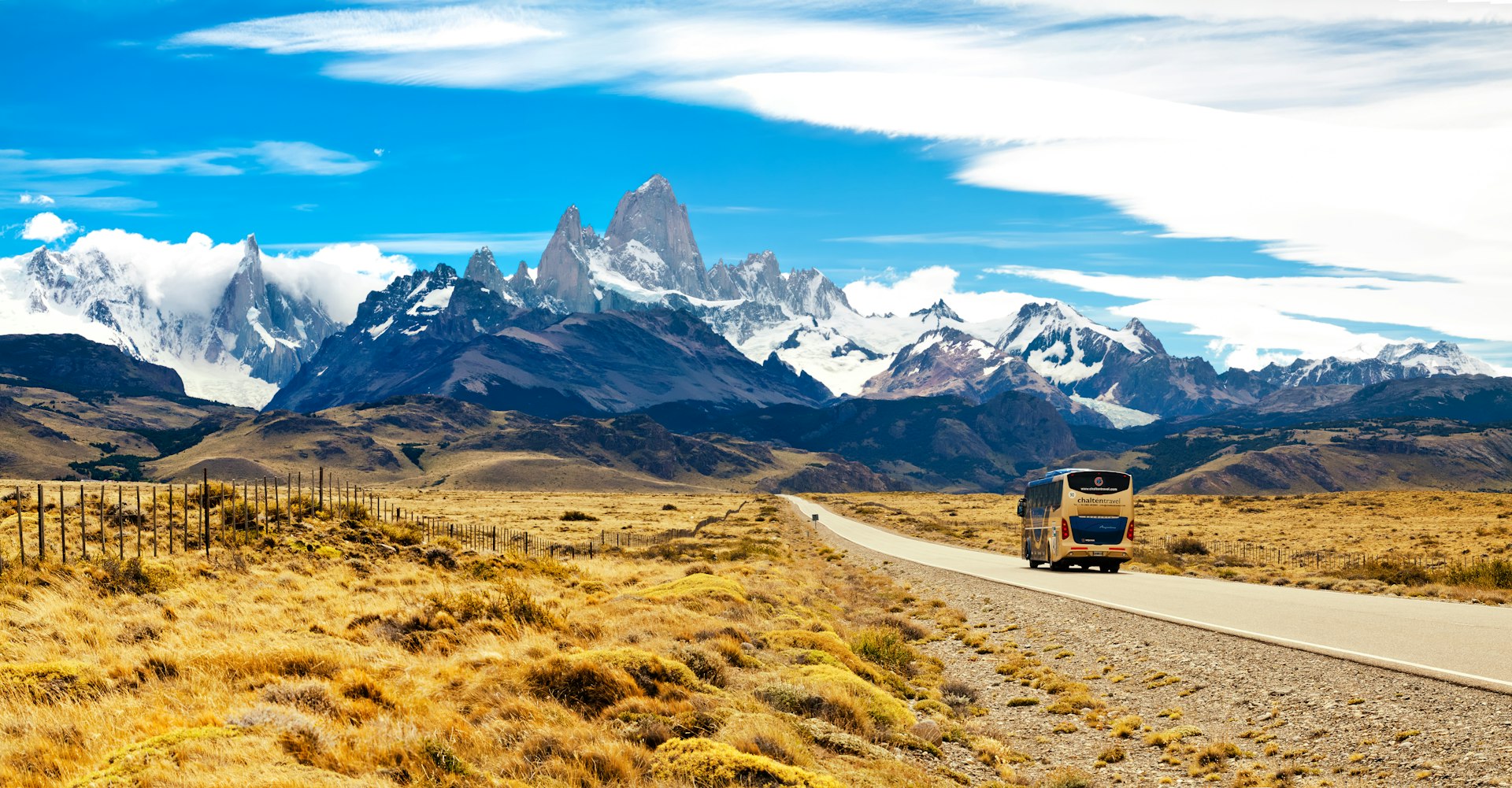 A bus travels on the road to El Chalten, toward the spectacular peaks of Mt Fitzroy and Cerro Torre in the distance