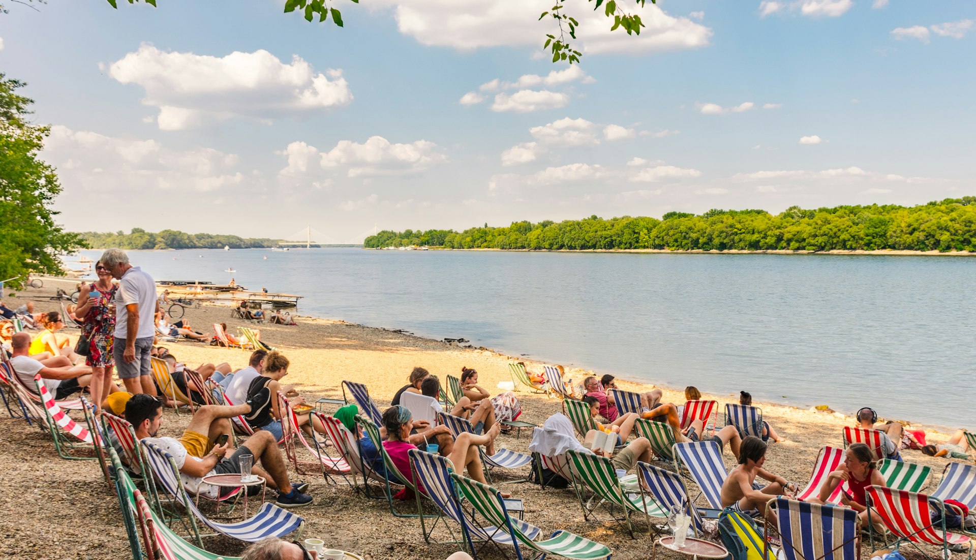 People relaxing in deck chairs on a beach by the Danube River, Budapest