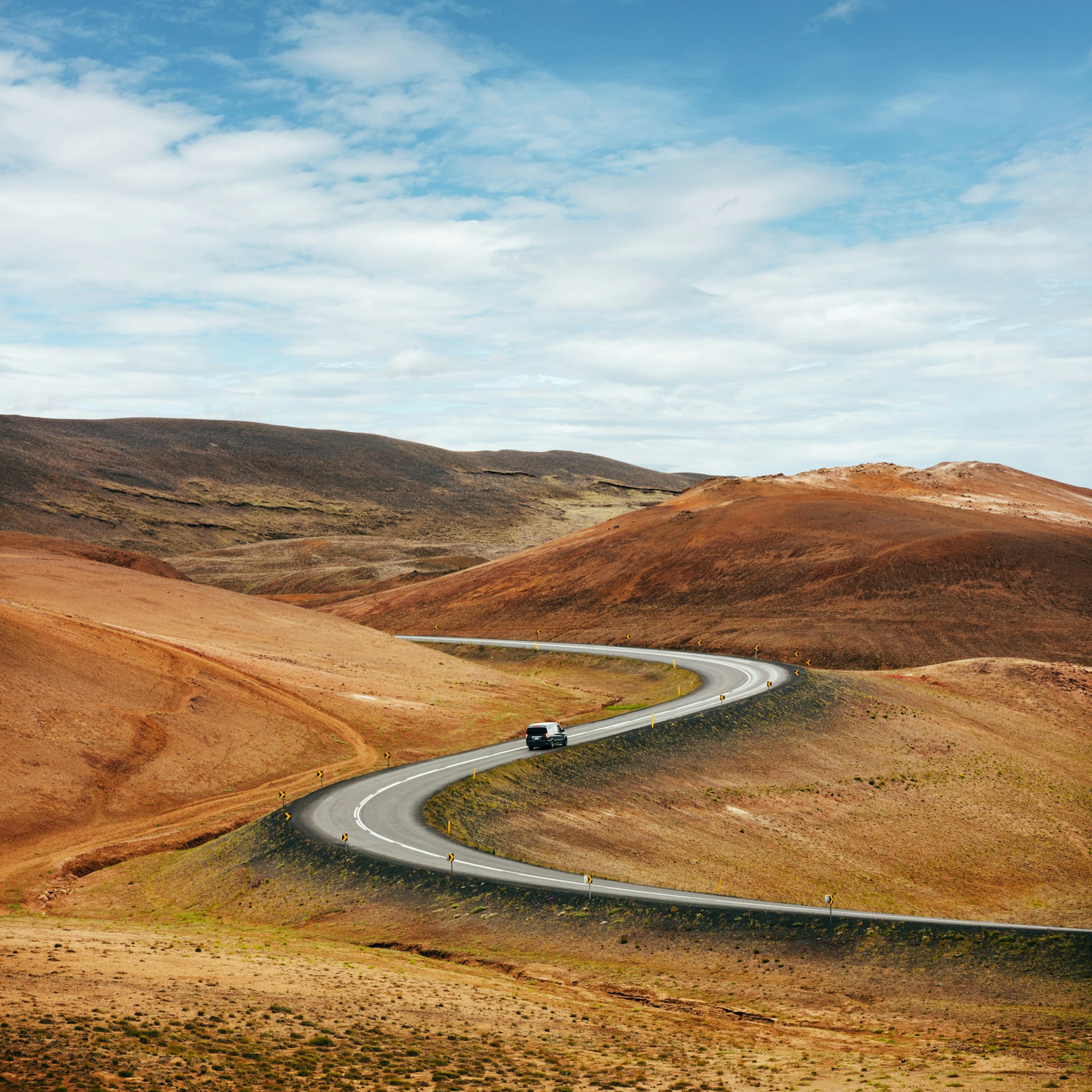 A road zigzaggin through a barren landscape, with blue skies above