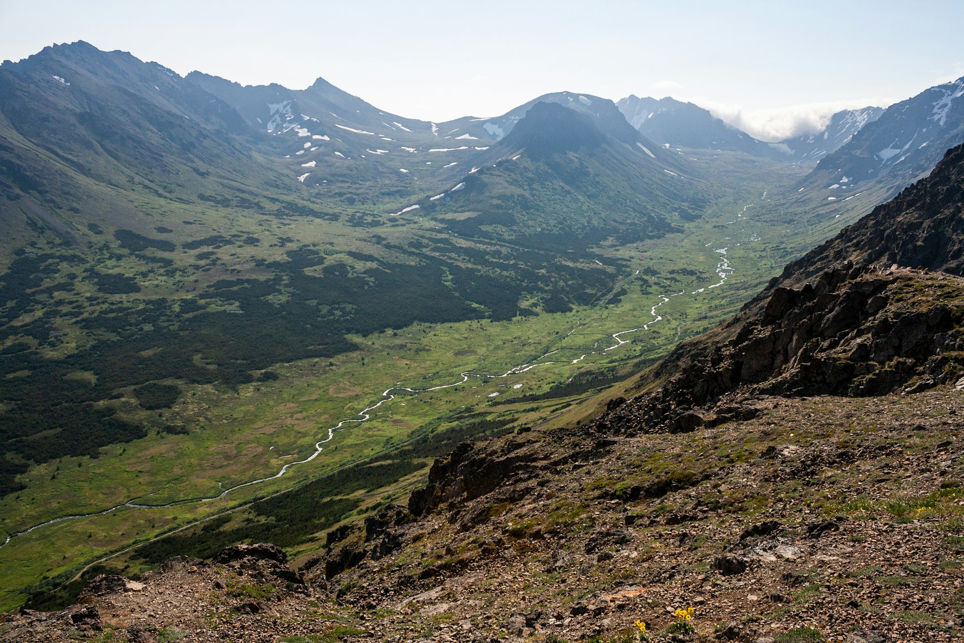 A mountain valley seen from above, with a narrow river below