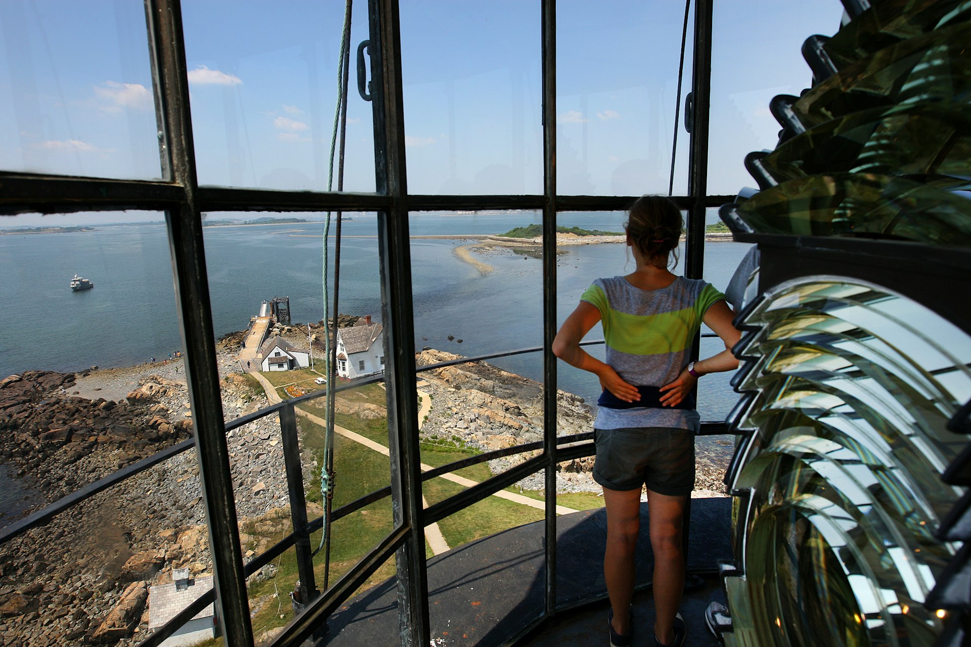 A woman stands inside the top of the Boston Light overlooking Boston Harbor Islands.