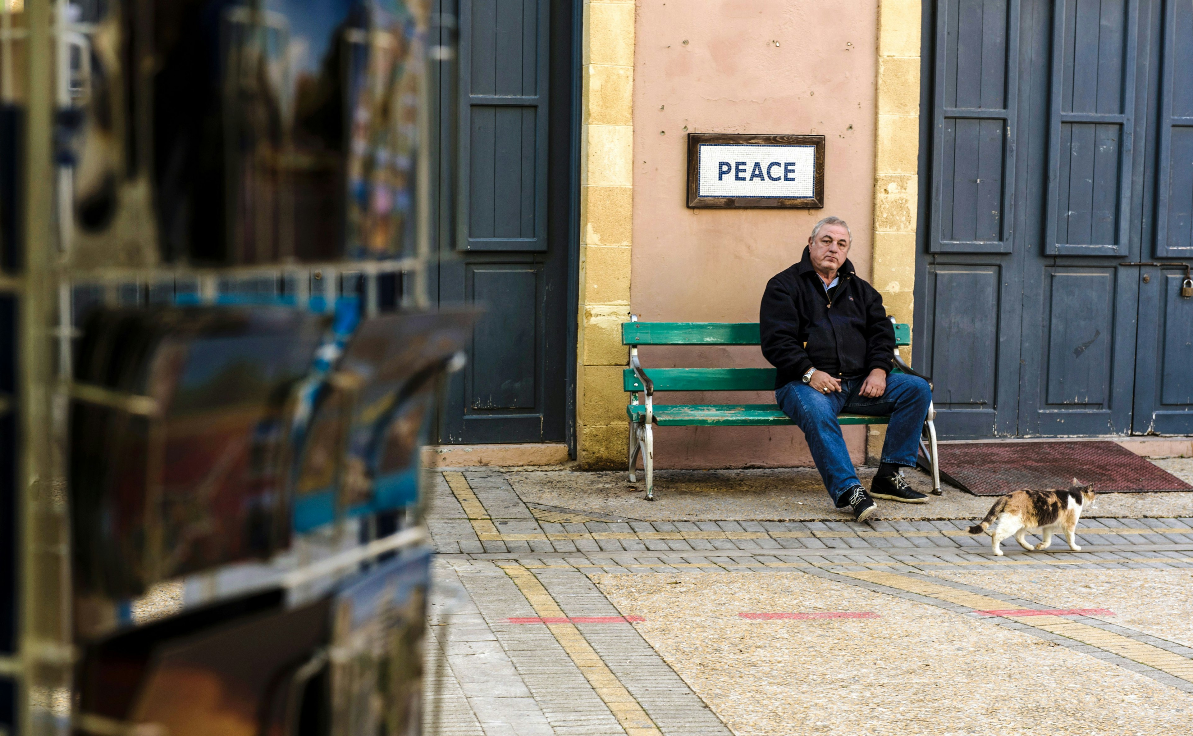 A man sits on a bench beneath a sign saying