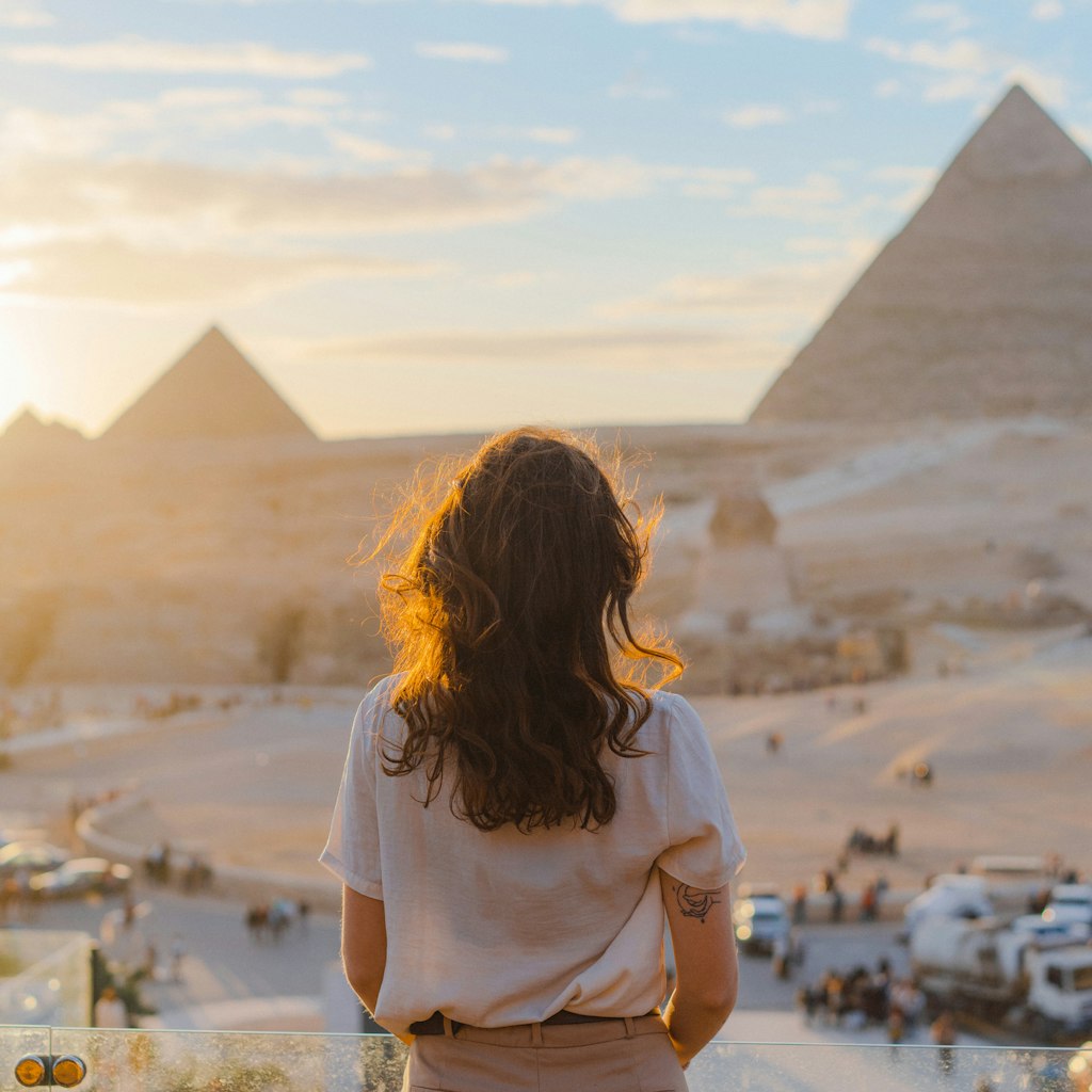 Young Caucasian woman standing on the  terrace on the  background of Giza pyramids