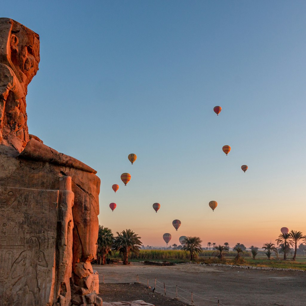 Colossi of Memnon at dawn with hot air balloons in the sky, Luxor, Nile Valley, Egypt