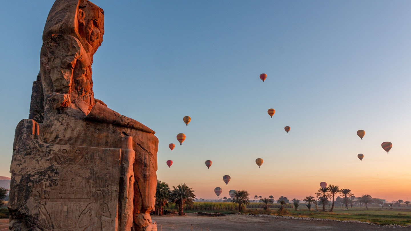 Colossi of Memnon at dawn with hot air balloons in the sky, Luxor, Nile Valley, Egypt