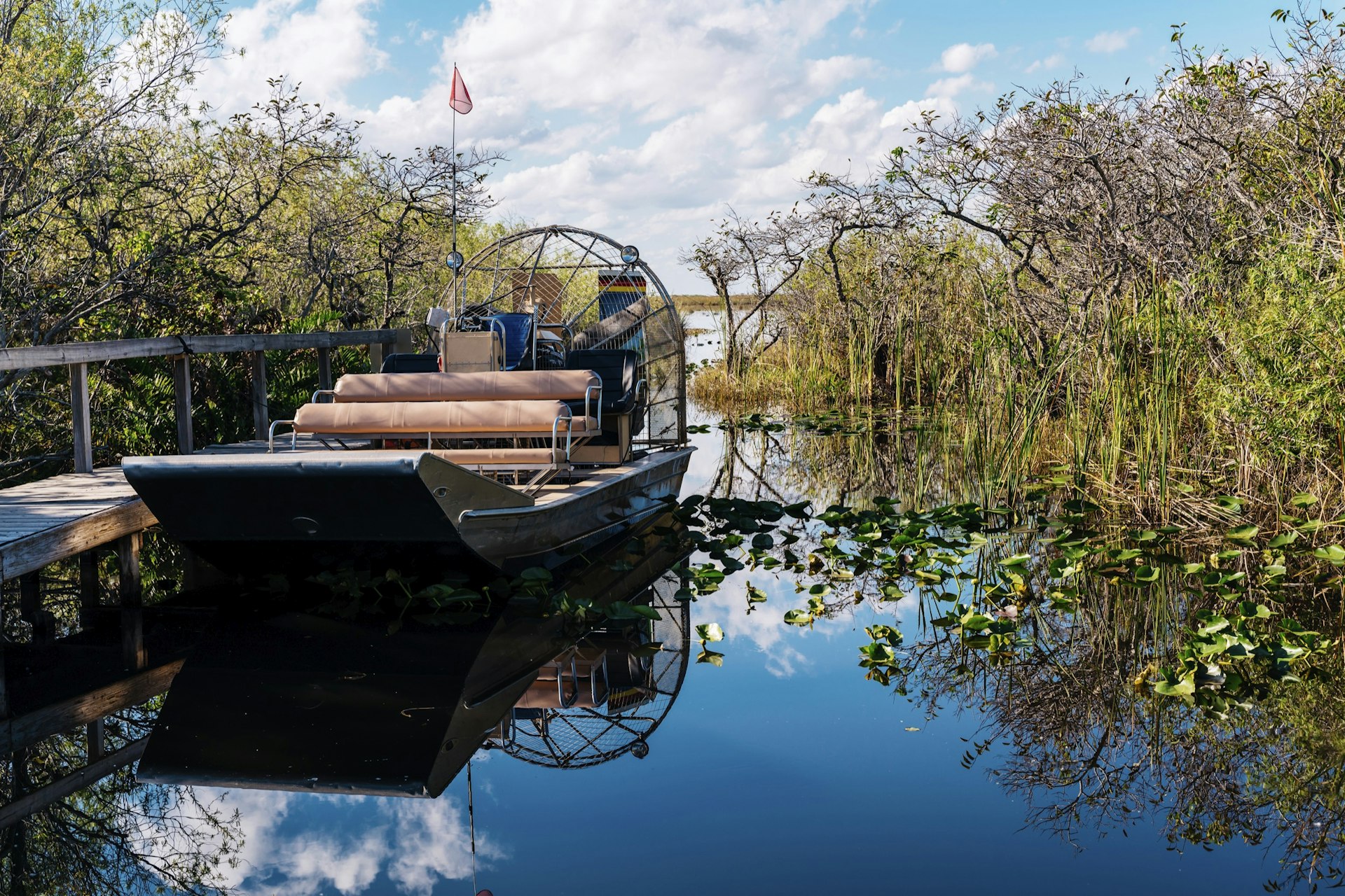 Airboat by pier in lake against sky at Everglades National Park