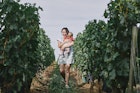 A woman carries her baby through the vines of a French vineyard